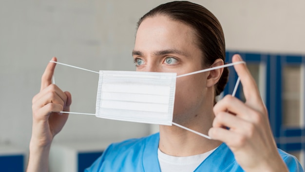 Männliche Krankenschwester, die medizinische Maske aufsetzt