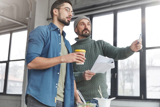 Männliche Mitarbeiter im Büro mit Mittagessen