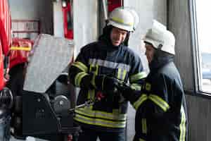 Kostenloses Foto männliche und weibliche feuerwehrleute arbeiten in anzügen und helmen zusammen