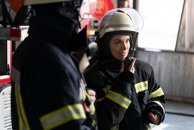 Männliche und weibliche Feuerwehrleute arbeiten in Anzügen und Helmen zusammen