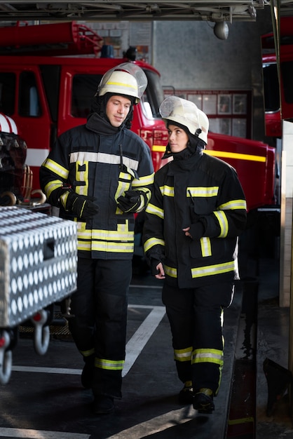 Männliche und weibliche Feuerwehrleute arbeiten in Anzügen und Helmen zusammen