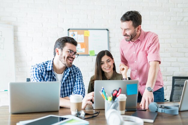 Männliche und weibliche Geschäftsleute, die über Laptop kommunizieren, treffen sich am Arbeitsplatz