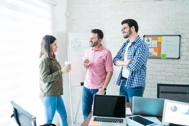 Männliche und weibliche Kollegen unterhalten sich beim Kaffeetrinken im Besprechungsraum im Büro