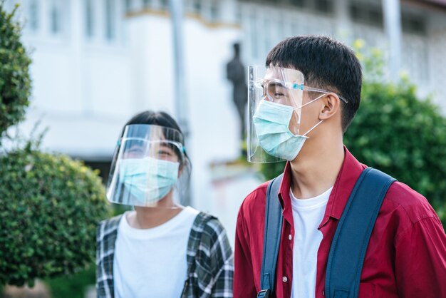 Männliche und weibliche Schüler tragen Gesichtskälte und Masken. Gehen Sie den Fußweg entlang