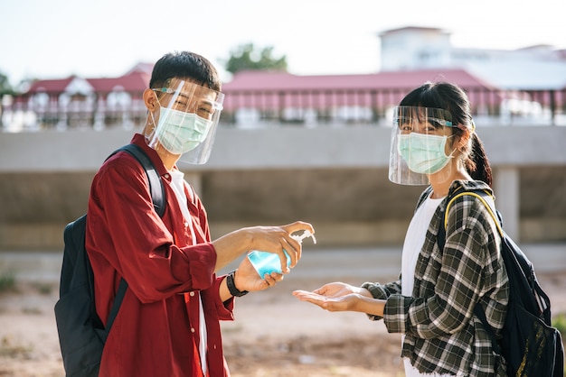 Männliche und weibliche schüler tragen masken und drücken das gel, um ihre hände zu waschen.