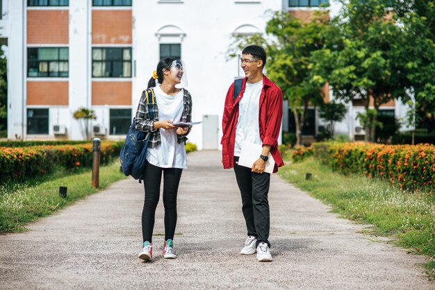 Männliche und weibliche Studenten tragen ein Gesicht Chill und stehen vor der Universität.