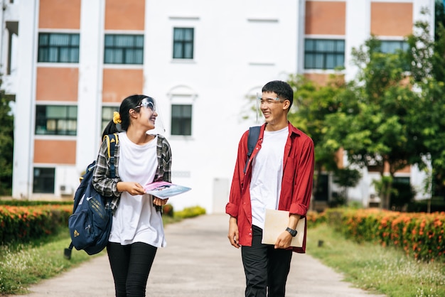 Männliche und weibliche Studenten tragen ein Gesicht Chill und stehen vor der Universität.