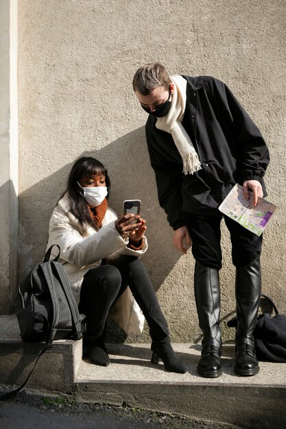 Männliche und weibliche Touristen, die ihr Smartphone im Freien überprüfen