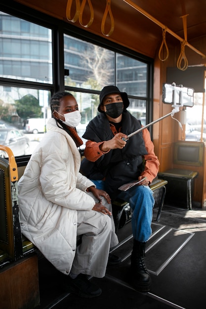 Männliche und weibliche Touristen, die sich im Bus selbst machen, während sie medizinische Masken tragen