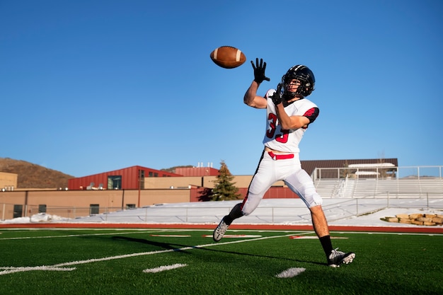 Männlicher amerikanischer Fußballspieler in Uniform auf dem Feld