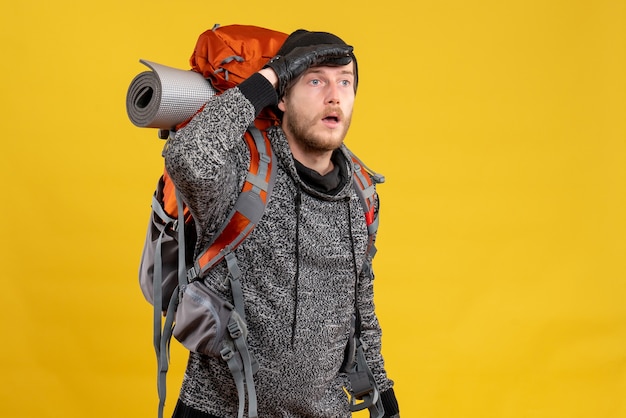 Kostenloses Foto männlicher anhalter mit lederhandschuhen und rucksack, der etwas ansieht