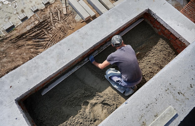 Männlicher Arbeiter beim Estrichboden auf der Baustelle