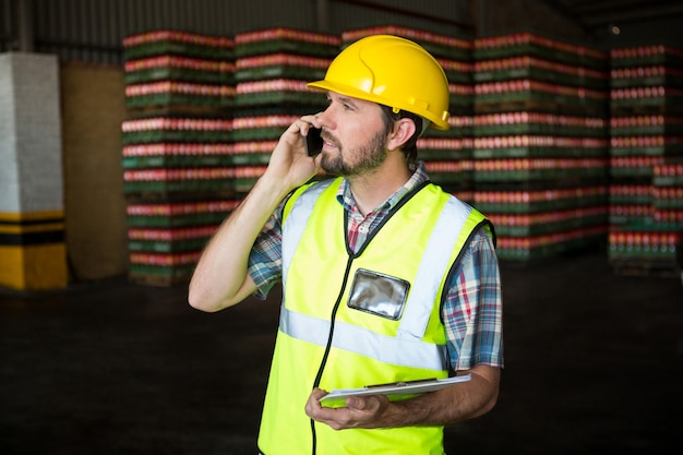 Männlicher Arbeiter, der am Telefon in der Fabrik spricht