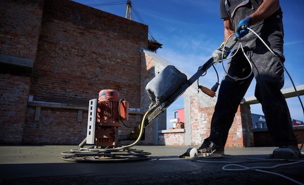 Kostenloses Foto männlicher arbeiter, der auf der baustelle eine betonestrichmaschine verwendet