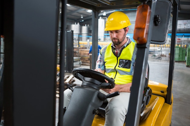 Männlicher Arbeiter, der im Gabelstapler sitzt