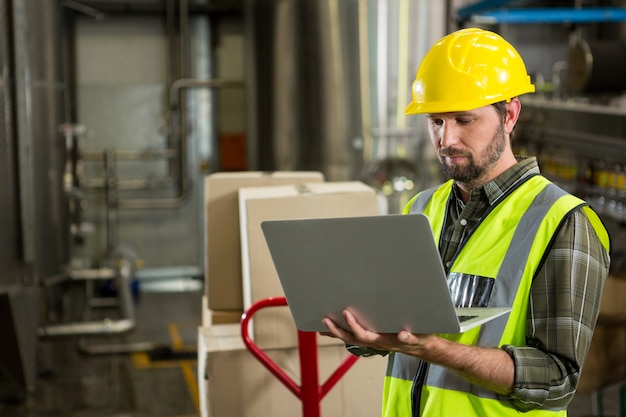 Männlicher Arbeiter, der Laptop im Verteilungslager verwendet