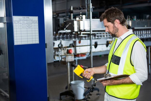 Männlicher Arbeiter, der Maschinen an der Saftfabrik benutzt