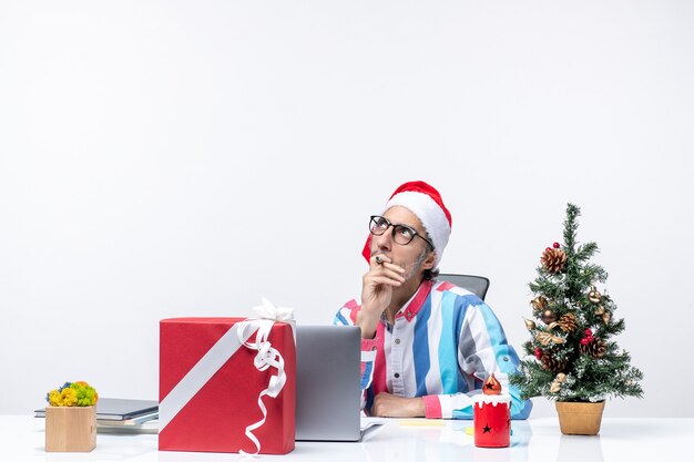 Männlicher Arbeiter der Vorderansicht, der an seinem Platz mit Laptop und Akten sitzt, die Weihnachtsfeiertagsbürojob arbeiten