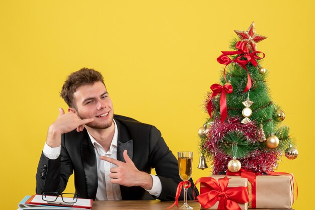 Männlicher Arbeiter der Vorderansicht, der hinter seinem Arbeitsplatz auf Gelb sitzt