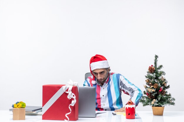 Männlicher Arbeiter der Vorderansicht, der mit Laptop an seinem Platz sitzt