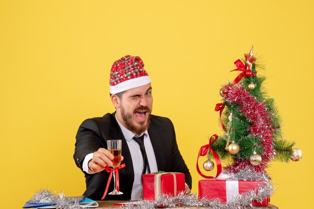 Männlicher Arbeiter der Vorderansicht, der Weihnachten mit Champagner auf Gelb feiert