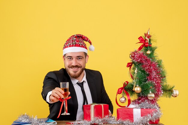 Männlicher Arbeiter der Vorderansicht, der Weihnachten mit Champagner auf Gelb feiert