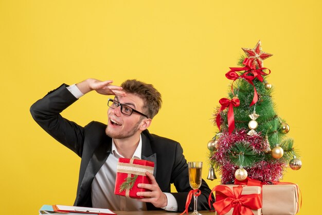 Männlicher Arbeiter der Vorderansicht hinter seinem Arbeitsplatz mit Geschenken auf Gelb