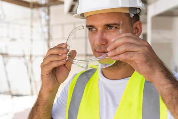 Männlicher arbeiter im bau, der schutzausrüstung trägt