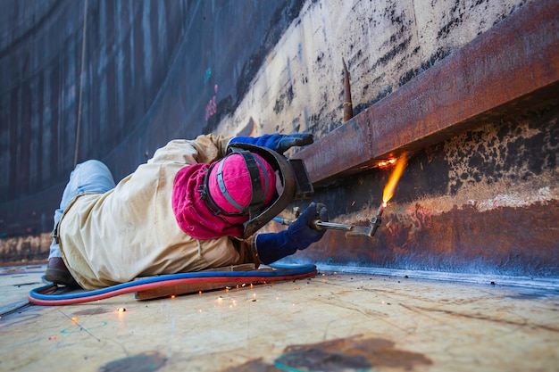 Männlicher arbeiter metallschneidefunke auf panzerschale platte starke hintere stahlplatte mit schneidblitz.