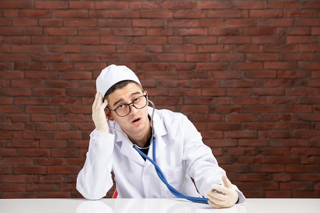 Männlicher Arzt der Vorderansicht im weißen medizinischen Anzug mit Stethoskop
