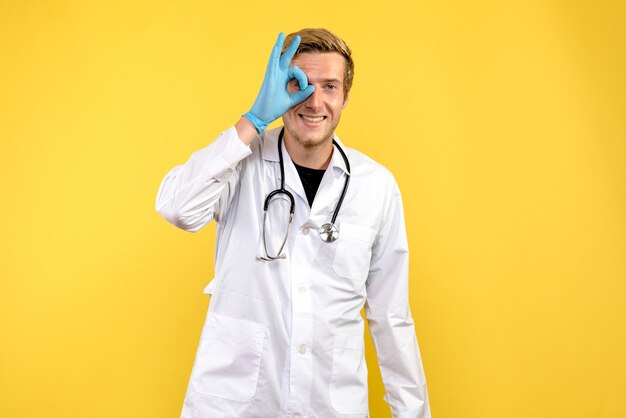 Männlicher Arzt der Vorderansicht lächelnd auf gelbem Hintergrundgesundheitsvirusmediziner
