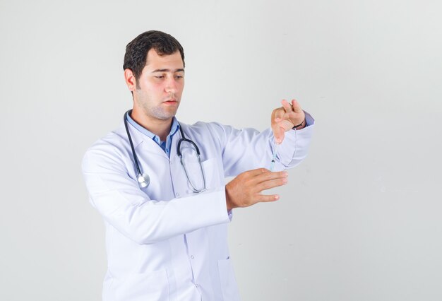 Männlicher Arzt hält Spritze zur Injektion in weißen Kittel