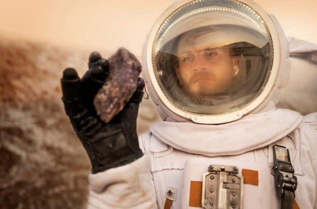 Männlicher Astronaut, der während einer Weltraummission auf einem anderen Planeten einen Felsen analysiert
