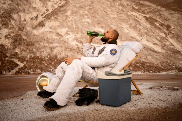 Männlicher Astronaut, der während einer Weltraummission auf einem unbekannten Planeten ein Bier trinkt