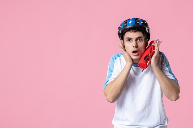 Männlicher Athlet der Vorderansicht in der Sportkleidung mit Helm und Flasche Wasser