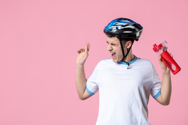 Männlicher Athlet der Vorderansicht in der Sportkleidung mit Helm und Flasche Wasser