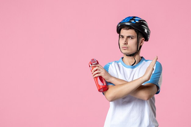 Männlicher Athlet der Vorderansicht in der Sportkleidung mit Helm und Flasche Wasser