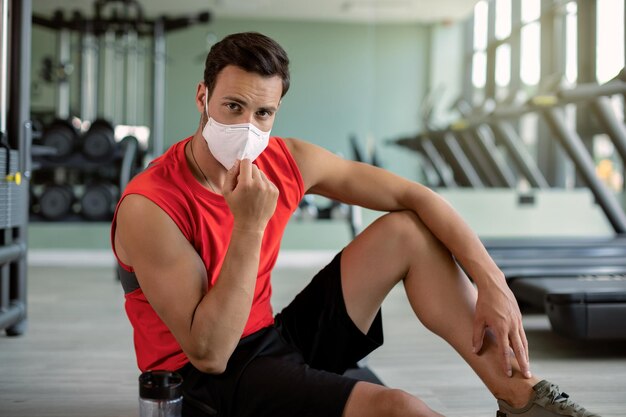 Männlicher Athlet mit schützender Gesichtsmaske in einem Fitnessstudio aufgrund der COVID19-Epidemie