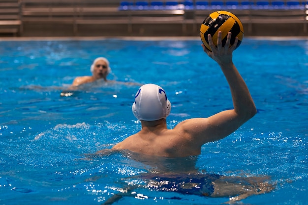 Männlicher Athlet spielt Wasserball im Hallenbad