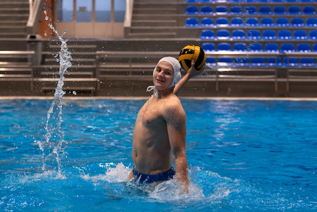 Männlicher Athlet spielt Wasserball im Hallenbad