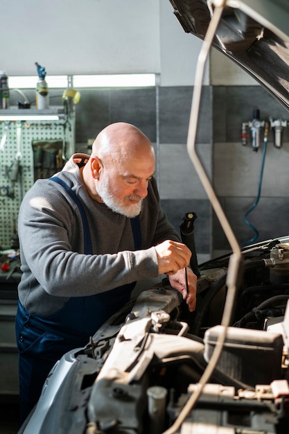 Kostenloses Foto männlicher automechaniker, der in der autowerkstatt arbeitet