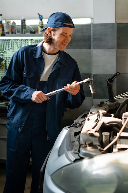 Kostenloses Foto männlicher automechaniker, der in der autowerkstatt arbeitet