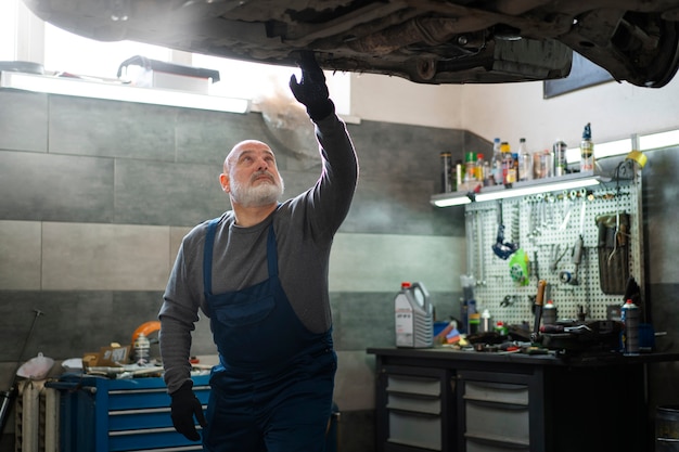 Kostenloses Foto männlicher automechaniker, der in der autowerkstatt arbeitet