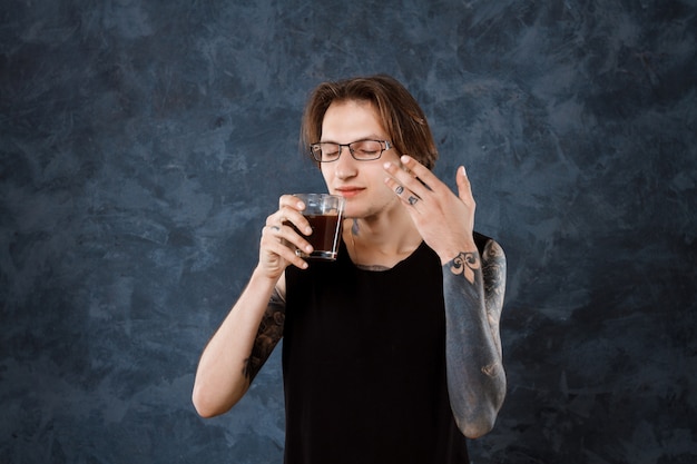 Männlicher Barista, der Geruch von Kaffee über Grau genießt.