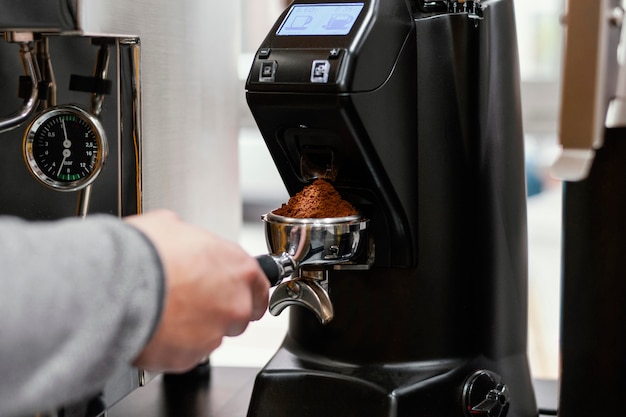 Männlicher Barista unter Verwendung der Kaffeemaschinenschale