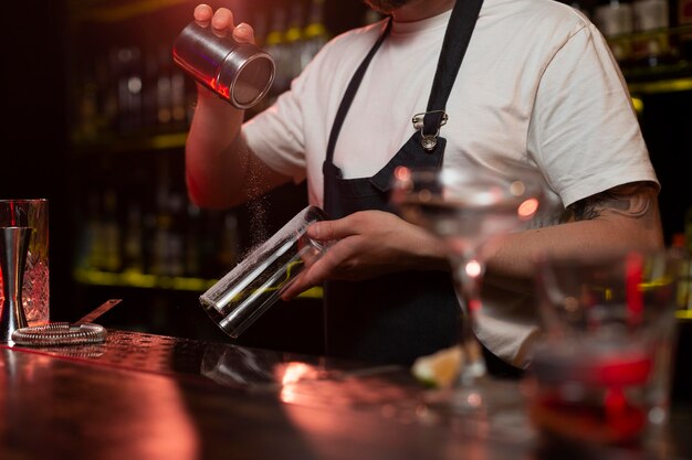 Männlicher Barkeeper macht einen Cocktail mit einem Shaker