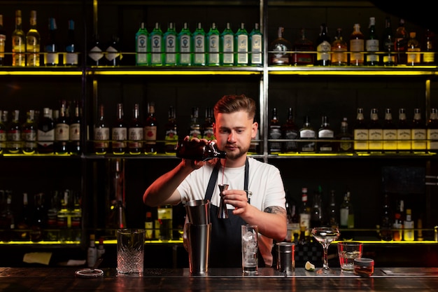 Männlicher Barkeeper macht einen Cocktail mit einem Shaker