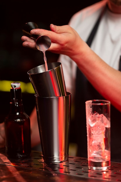 Männlicher barkeeper macht einen cocktail mit einem shaker