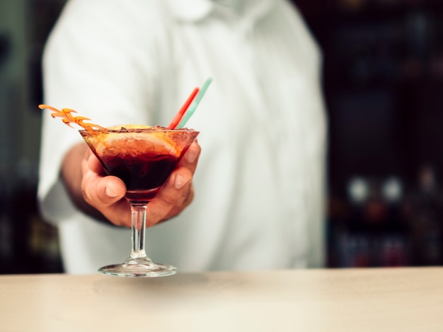 Männlicher Barmixer, der vibrierendes Getränk im Martini-Glas dient