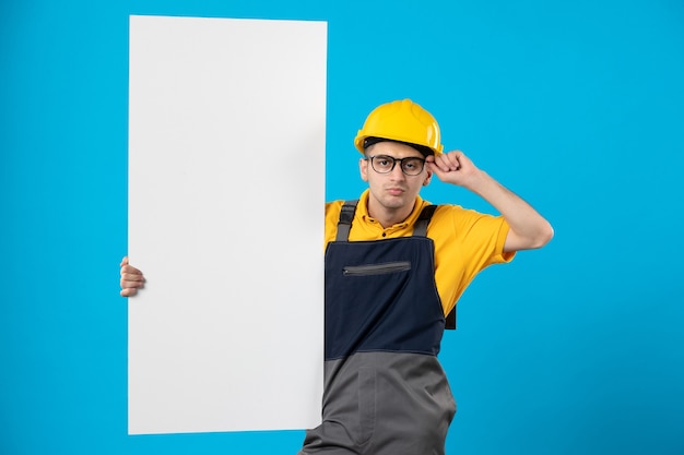 Kostenloses Foto männlicher baumeister der vorderansicht in der uniform mit papierplan auf blau